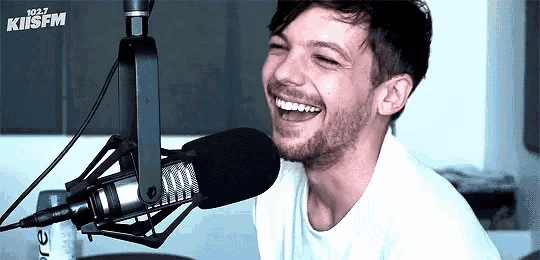 a man with a beard is smiling in front of a microphone .