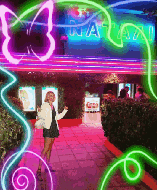 a woman stands in front of a neon sign that says nata