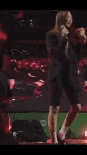 a woman in a black jacket and pink tights is dancing on a stage