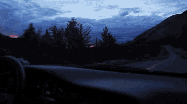 a car is driving down a road at night with a mountain in the background