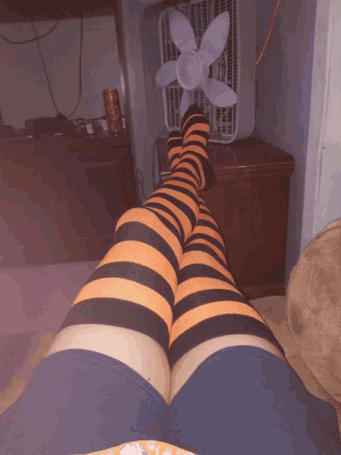 a person wearing orange and black striped socks is laying on a couch