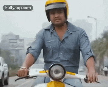 a man wearing a helmet is riding a motorcycle down a street .