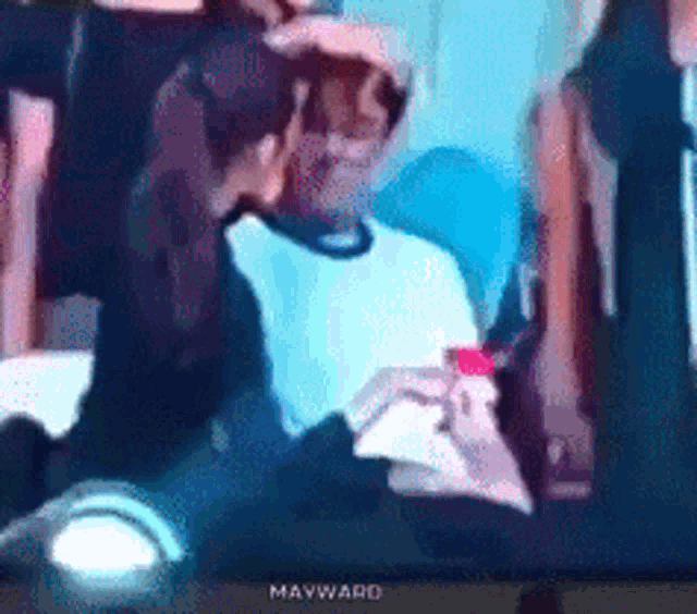 a mayward tv screen shows a man in a white shirt holding a red object