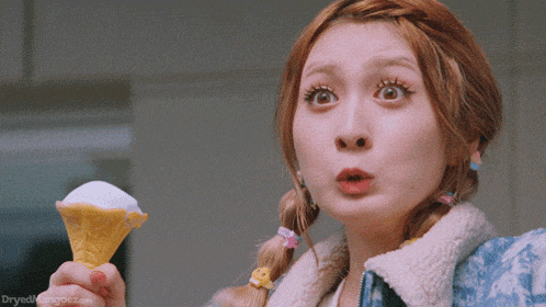 a woman holding an ice cream cone with a surprised look on her face and the words dryedmangoez.com visible