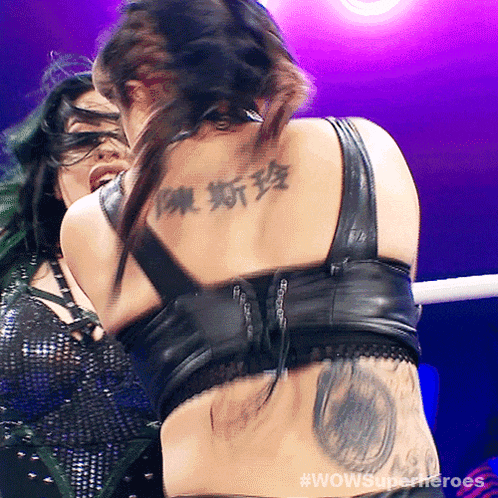 a woman with a tattoo on her back is fighting another woman with green hair