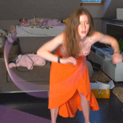 a woman in an orange dress is dancing in a room