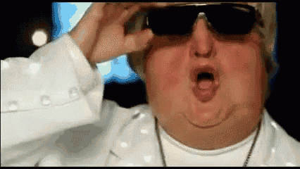a man wearing sunglasses and a white jacket is making a funny face .