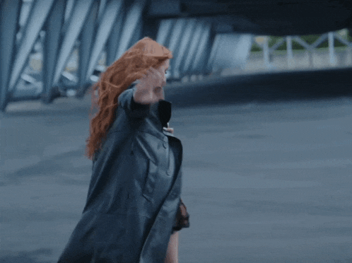 a woman with red hair wearing a black coat