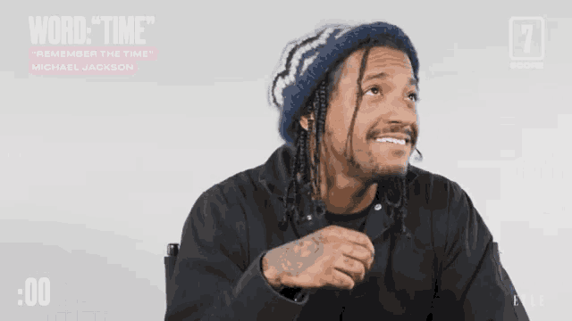 a man with dreadlocks is smiling in front of a screen that says word time