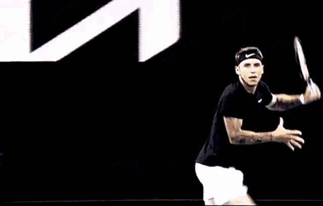 a man is swinging a tennis racquet in front of a sign that says kia