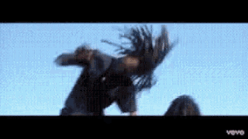 a man with dreadlocks is flying through the air in a video .