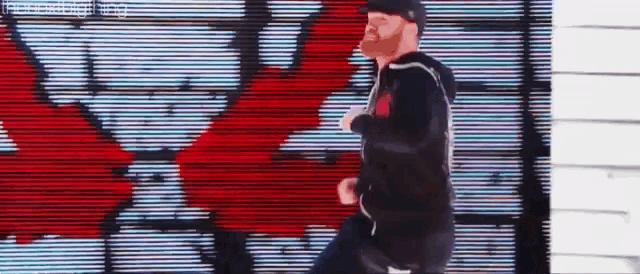a man with a red beard is running in front of a graffiti wall .