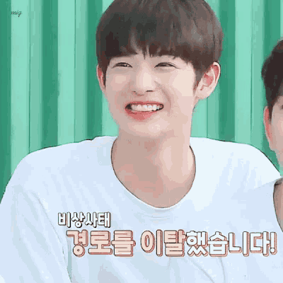 a young man wearing a white t-shirt is smiling with a green background .