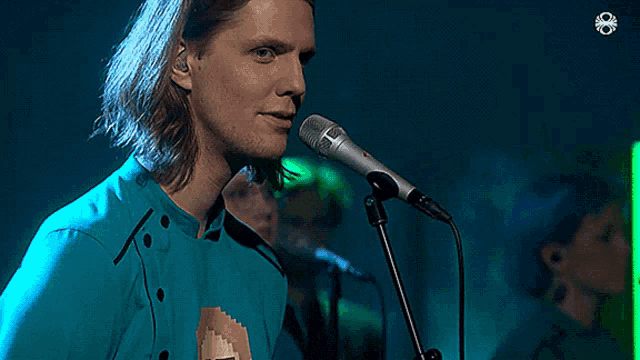 a man singing into a microphone with a green background