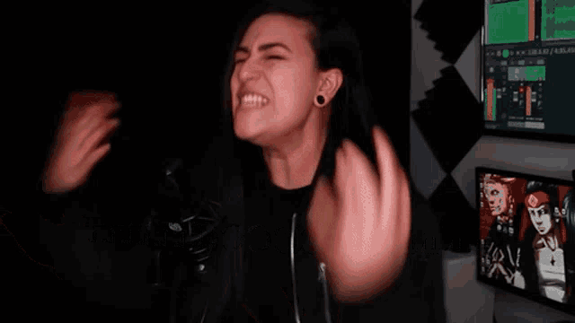 a woman in a black jacket is making a funny face in a dark room