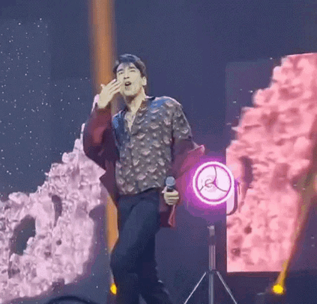 a man is singing into a microphone on stage .