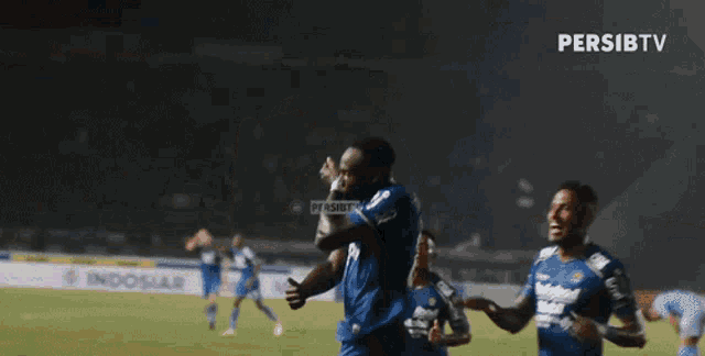 two soccer players are hugging each other on a field sponsored by persibtv