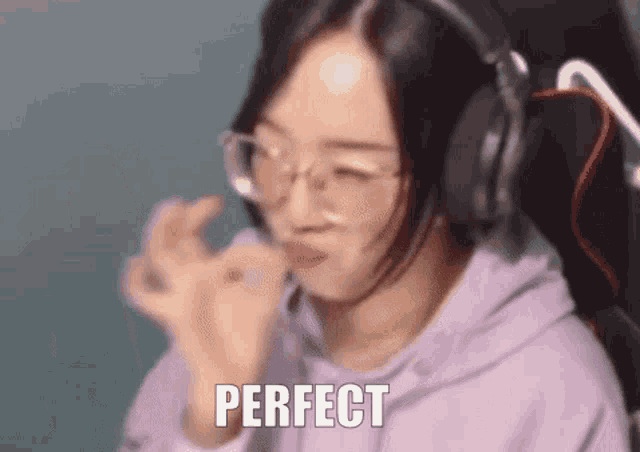 a woman wearing headphones and glasses is sitting in a chair and making a perfect gesture .