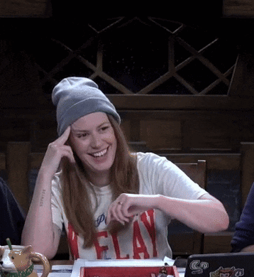 a woman wearing a t-shirt that says " flay " smiles while sitting at a table