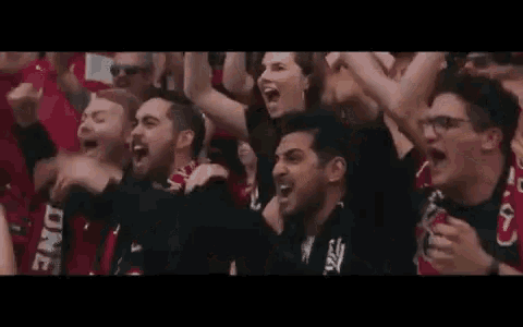 a group of people are sitting in a stadium watching a soccer game and cheering .