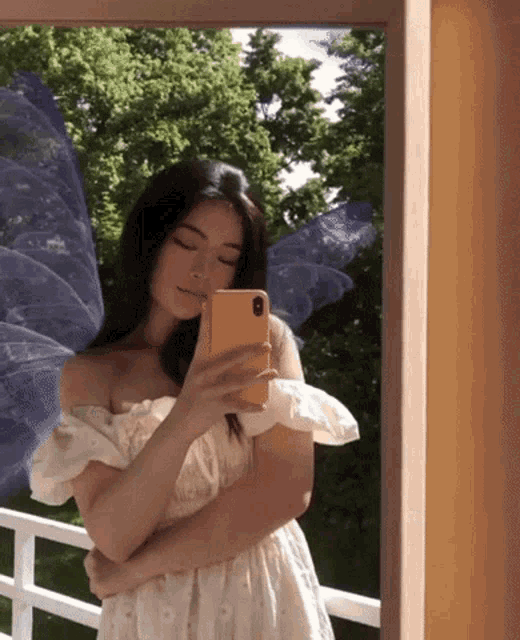 a woman in a white dress is taking a picture of herself in a mirror