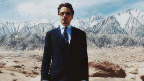 a man in a suit and tie is standing in front of mountains