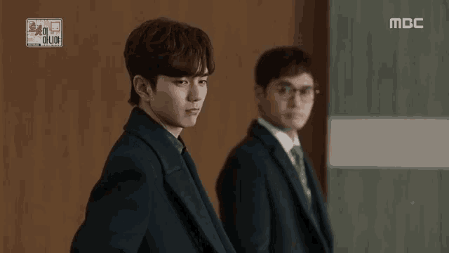two men in suits are standing next to each other and one of them is smiling