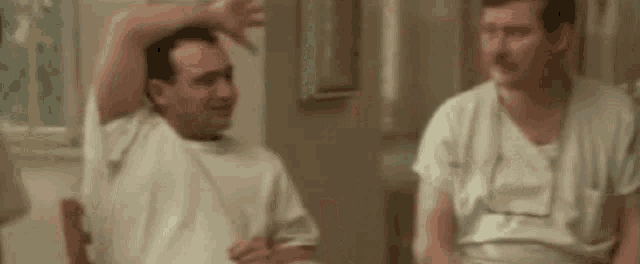 a group of men in white shirts are sitting in a room with their arms outstretched .