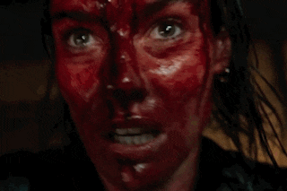 a close up of a woman 's face covered in blood and smiling .