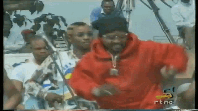 a man in a red hoodie is dancing in front of a crowd with the letters rtnc on the bottom