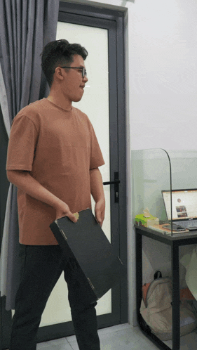 a man in a brown t-shirt is holding a black box