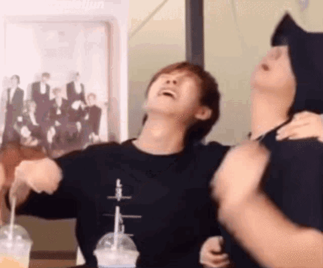 a couple of men are standing next to each other and laughing .