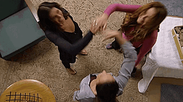 three women are standing in a circle with their hands in the air