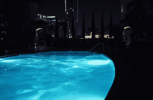 a swimming pool is lit up at night with the word marriott visible in the background