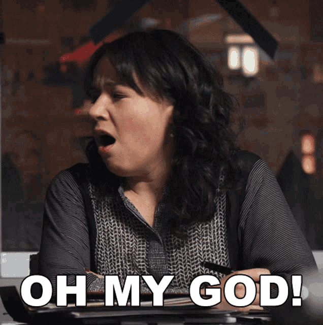a woman sitting at a desk with the words oh my god on her face