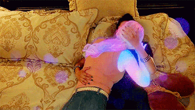 a woman is laying on a bed with a purple light behind her .