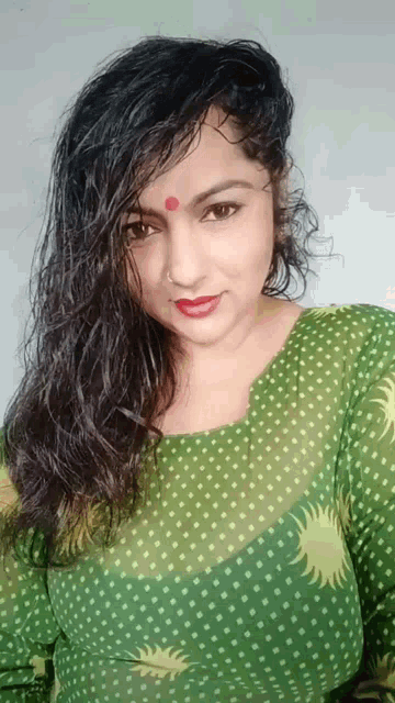 a woman with a red dot on her forehead is wearing a green polka dot top
