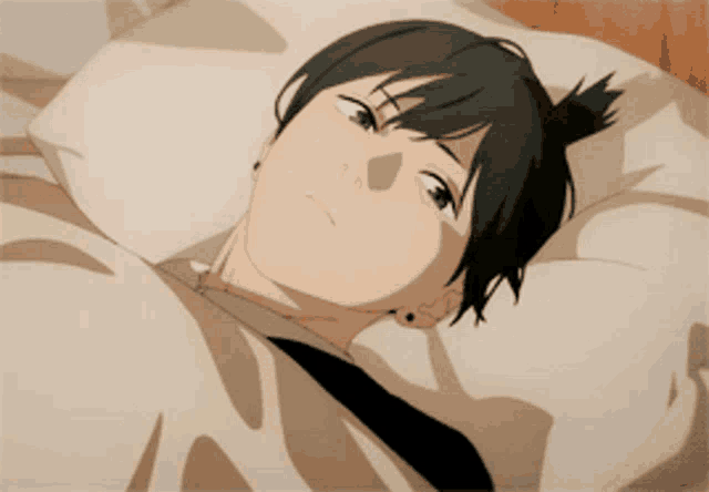 a man with black hair is laying on a bed