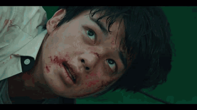 a young man with blood on his face looks up at the sky