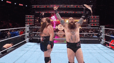 two wrestlers are standing in a wrestling ring with one holding a world heavyweight championship