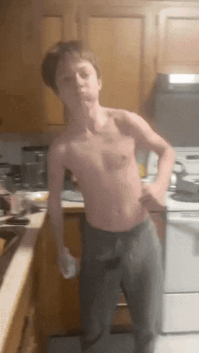 a young boy without a shirt is standing in a kitchen with his hands on his hips