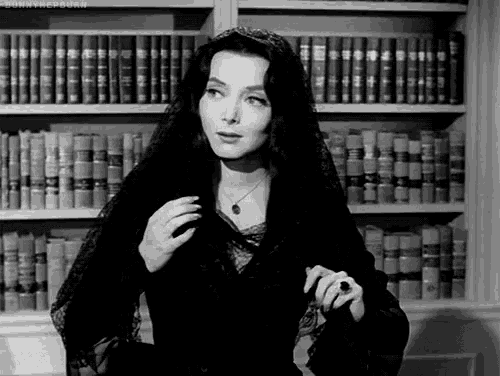 a black and white photo of a woman in front of bookshelves