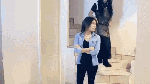 a woman in a long black dress is standing next to a woman in a blue shirt .