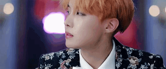 a close up of a young man wearing a floral suit and white shirt .