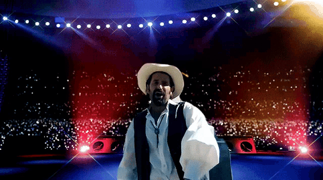 a man in a cowboy hat is standing on a stage in front of a crowd