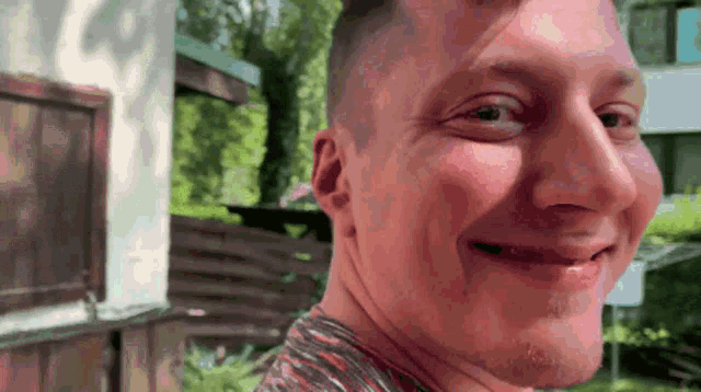 a close up of a man 's face with a blurred background and a fence in the background