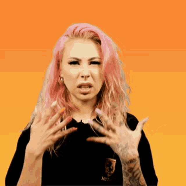 a woman with pink hair is wearing a black shirt that says hufflepuff on it
