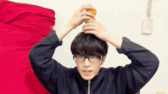 a man wearing glasses is holding a bottle on top of his head .