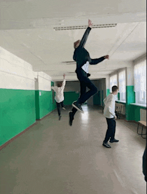 a man in a black jacket is jumping in the air in a hallway