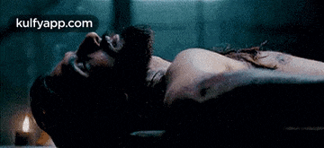 a man with a beard is laying on his back in a dark room with his eyes closed .